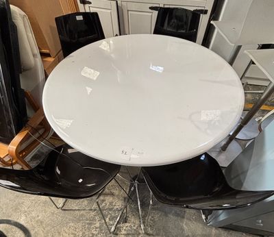 a white table with four black chairs around it