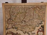 une vieille carte posée sur un support en bois, avec un mur de briques en arrière-plan