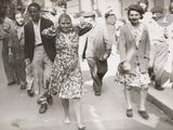 many people walking down the street in this old photo