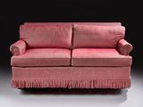 a pink couch with fringes on it in a dark room