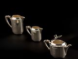 three pieces of silver teapots with lids on a black background