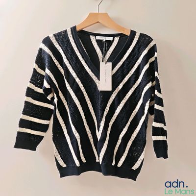 un pull rayé noir et blanc suspendu à un cintre accroché au mur