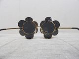 black flower shaped sunglasses with gold rims on a white surface