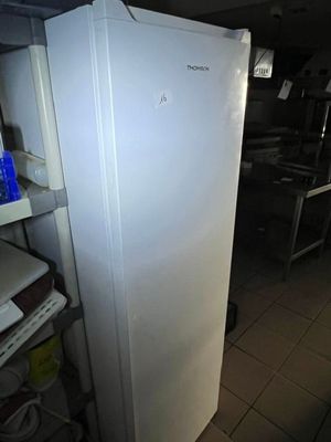 un réfrigérateur blanc posé dans une cuisine, à côté d'une étagère