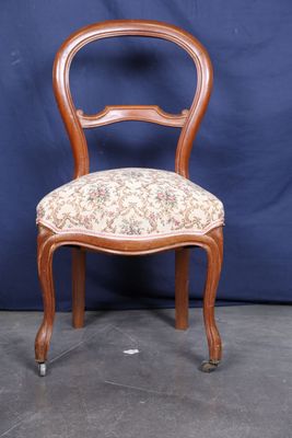 une image d'une chaise en bois dont l'assise est recouverte d'un rembourrage floral