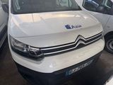 une camionnette blanche garée dans un parking à côté d'autres voitures