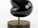an image of a black sculpture on a wooden base with a white background