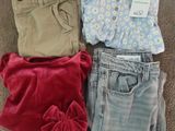 trois paires de vêtements pour bébé sont disposées par terre
