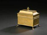 brass box with a lid on a stand on a black background