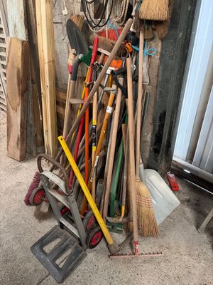 a pile of brooms and other tools in a garage
