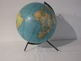 un petit globe bleu posé sur un socle noir, sur une surface blanche
