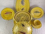yellow dishes and bowls with fish designs on them on a table