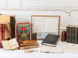 de nombreux livres anciens posés sur une table, à côté d'un cadre photo