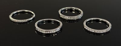 three silver rings with diamonds on a black surface