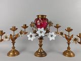 trois bougeoirs en or ornés de fleurs et un vase rouge