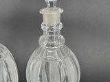 pair of clear glass perfume bottles with a glass stopper on the top