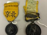 deux médailles portant des inscriptions en chinois, placées l'une à côté de l'autre