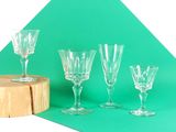 quatre verres à vin posés sur une table, à côté d'un morceau de bois
