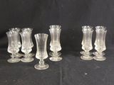 six clear glass vases are lined up on a black background