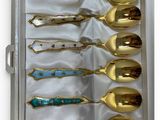 six spoons in a box that are gold and blue