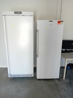 two white refrigerators sitting next to each other in a room