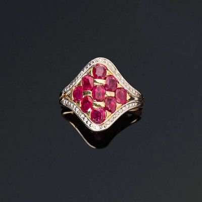un gros plan d'une bague sertie d'un diamant et d'un rubis sur une surface noire