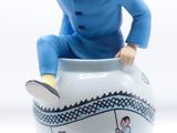 a figurine of a man sitting on top of a cup