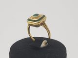 an image of a gold ring with a green stone in it