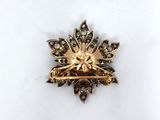 an image of a gold and diamond broochle on a white surface