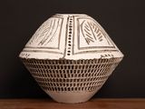 a white vase sitting on a table with a black background