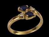 a close up of a gold ring with a blue sapphire and diamonds