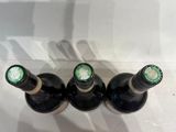 three bottles of wine are lined up on a shelf