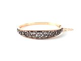un gros plan sur un bracelet jonc en or serti de diamants noirs et blancs