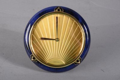 une horloge bleue et dorée posée sur une surface blanche