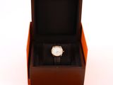 an orange box with a watch inside of it on a white surface