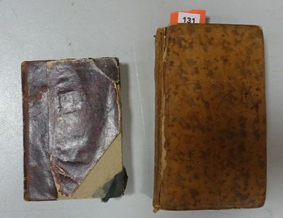 an old book sitting on top of a white table next to a brown book