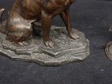 a bronze statue of a dog sitting on a rock