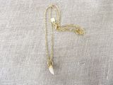 a gold chain necklace with a small white stone on it