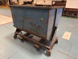 a blue dumpster sitting on a dolly in a warehouse