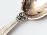 a silver spoon with a silver handle on a white surface