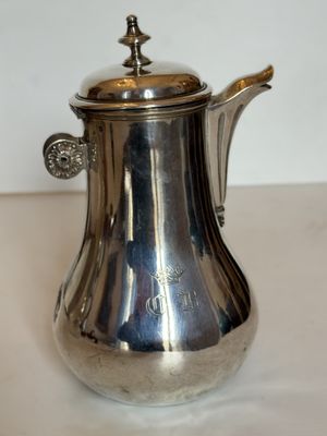 une cafetière en argent posée sur une table blanche