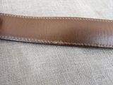 brown leather belt with white stitching on the side of it