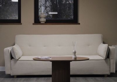 a white couch sitting in a living room next to two windows