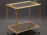 a brass bar cart with glass shelves on casteors