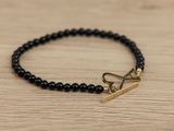a close up of a bracelet with a gold clasp on a wooden table