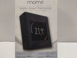 packaging of a black alarm clock sitting on top of a white table