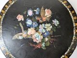 a black plate with a painting of flowers on it