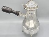 an antique silver coffee pot with a wooden handle on a white background
