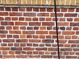 un lampadaire fixé à un poteau devant un mur de briques