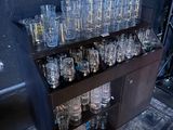 bottles and glasses on a shelf in a room with a blue wall